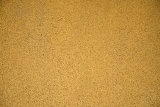Yellow painted stucco wall texture. Rough concrete surface background pattern for bright exterior architecture and blank decorative wallpaper.