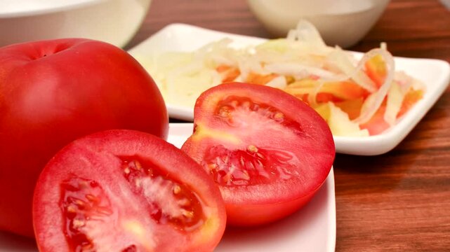 Fresh Red Tomato: Succulent slices on a white plate, ready to inspire your culinary creations. Close-up of sliced red tomatoes, an appetizing sight to awaken the taste buds.
