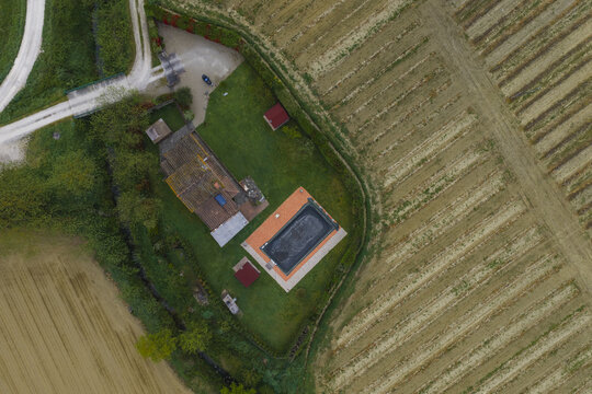 Aerial view of a rural house with a swimming pool surrounded by green lawns and cultivated fields in Castelfranco Piandisco, Tuscany, Italy.
