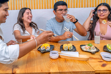 Friends enjoying nikkei sushi maki rolls dining restaurant © Guillermo Spelucin