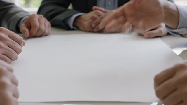 Business people discussing ideas around a blank paper table  