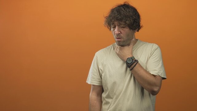 Man holding wristwatch with hand on throat, eyes closed and mouth open in a pained choking gesture in studio; throat discomfort.