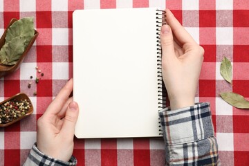 Obraz premium Woman with recipe book and different spices at table, top view