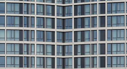 Obraz premium Modern Glass Building Facade with Repeating Window Patterns.