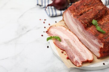 Fototapeta premium Pieces of smoked bacon and spices on white marble table, closeup. Space for text