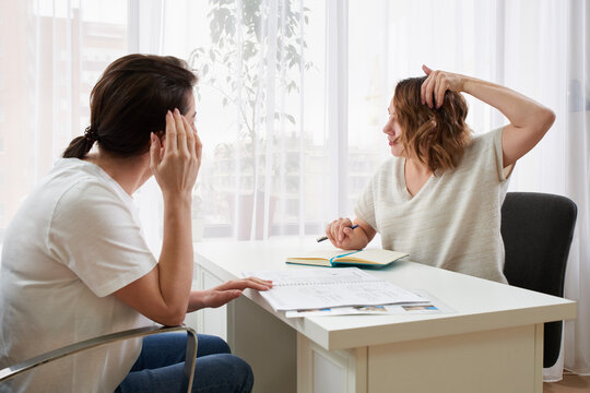 Doctor or massage specialist consulting young woman about headache