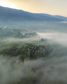 Aerial view of Le Balze del Valdarno rock formations and the village of Castelfranco Piandisco shrouded in morning mist at sunrise Castelfranco Piandisco, Tuscany, Italy.