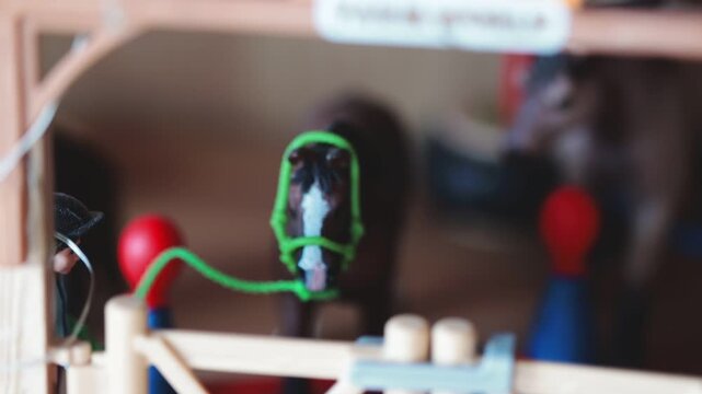 A small toy horse with a green rope wrapped around its neck, ideal for children's play or as a decorative element