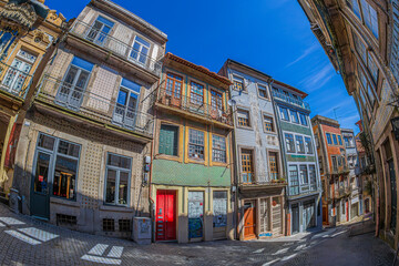 Obraz premium PORTO, PORTUGAL - APRIL 12, 2024: Rua dos Caldeireiros, a historic charming and vibrant sloping street with typical Portuguese architecture. Houses covered with colored tiles in the azulejo technique.