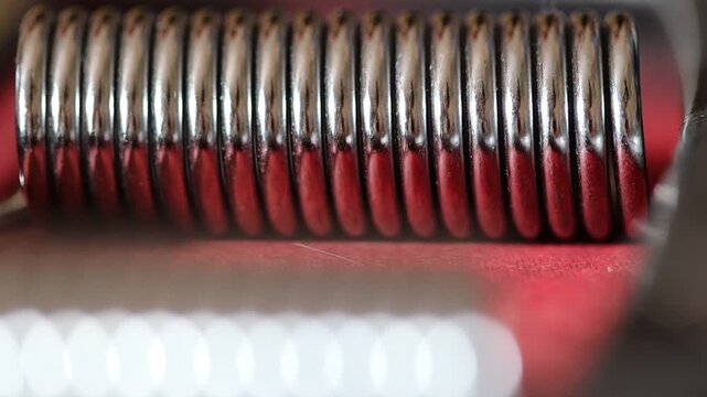 A stack of red and silver coils placed on a table, suitable for use in various settings such as industrial or scientific contexts