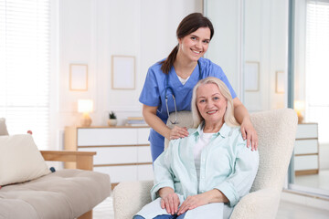 Fototapeta premium Portrait of smiling care worker with senior woman at nursing home. Space for text