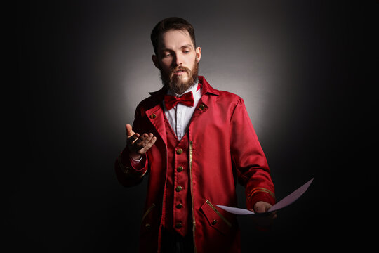 Professional actor in suit with script performing on black background with spotlight