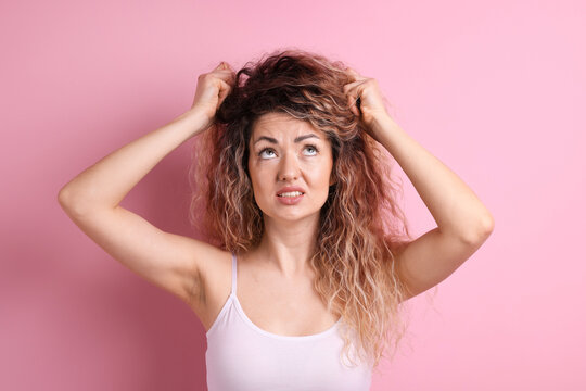 Unhappy woman with tangled hair on pink background
