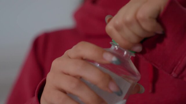 Homeowner Sealing Bottle. Individual Snugly Fastening Green Cap Onto Clear Drinking Container. Homeowner In Comfortable Indoors Environment Firmly Twisting Green Lid Onto Empty Bottle After Drinking