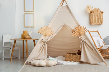 Stylish wigwam with dry leaves in child's room © New Africa