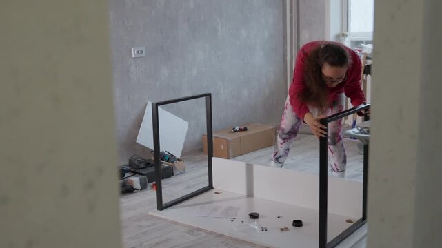 She Completes Furniture Assembly With Careful Inspection And Satisfaction. Woman Successfully Constructs And Verifies Furniture Stability With Content Expression And Organized Surroundings