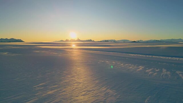 Frozen Landscape Illuminated By Sunset. Aerial Of Polar Ice And Distant Mountains of Antarctica