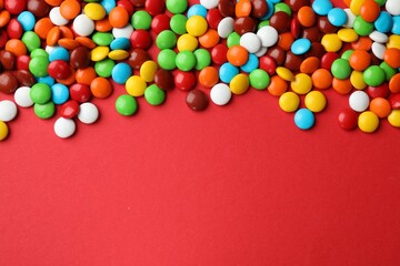 Obraz premium Delicious colorful candies on red background, top view. Space for text