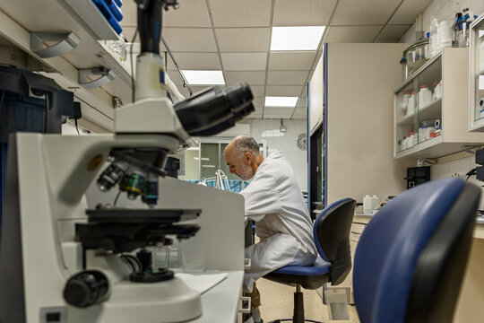 Scientist in a laboratory with a microscope in the foreground