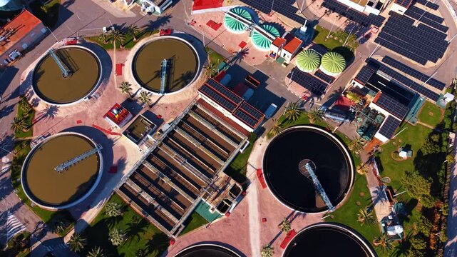 Flying over the territory of modern water recycling plant. Waterworks facility with solar panels and plants.