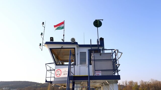 hungarian flag waving above ferry control tower on lake balaton with navigation equipment, railings and clear sky forming a precise view of local transport infrastructure on the water