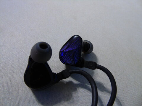 Modern blue in-ear monitors headphones on light textured background, close up