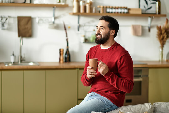 Handsome man enjoys his coffee at home while relaxing on a cozy sofa