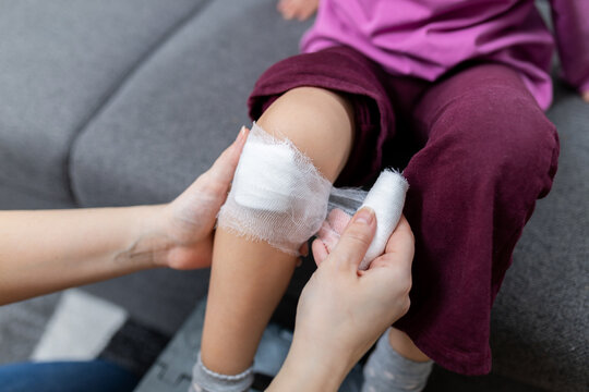 Parent wrapping bandage on child knee after minor injury at home