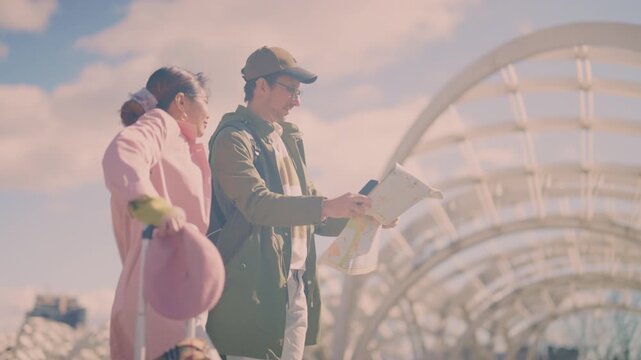 Diverse tourists navigate a city street with a map and smartphone, trying to find their way. Two visitors appear to be lost while exploring a modern urban area.