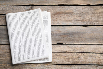 Naklejka premium Folded newspaper on wooden background, top view