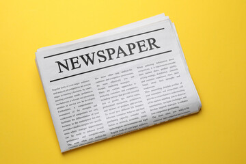 Naklejka premium Folded newspaper on orange background, top view