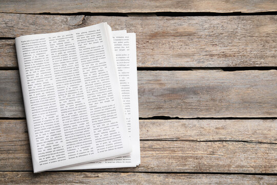 Folded newspaper on wooden background, top view