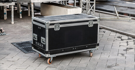 Black transport case stands on paved ground © kvdkz