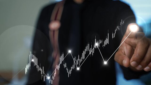 Close up of hand pointing at glowing business chart, Hand holding up a glowing graph of stock market growth with an arrow pointing upwards