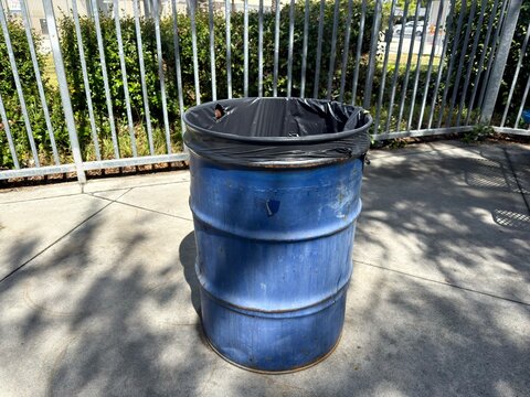 Industrial Outdoor Waste Bin: A large blue barrel-style trash can with a black liner, designed for high-traffic public facilities and industrial waste management.