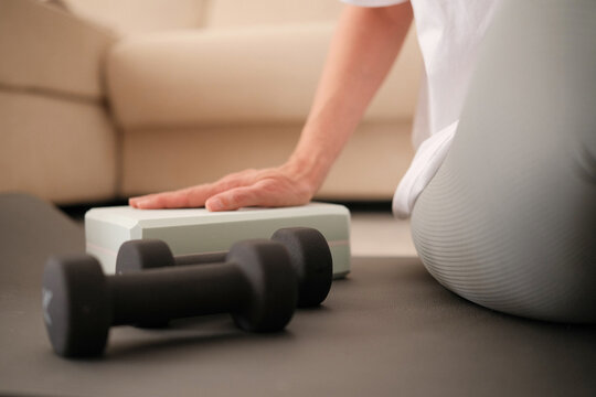 Woman ready to sport exercises at home. Sport workout on yoga mat with yoga block, dumbbells