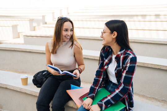 Happy students sitting on stairs and conversing about class project
