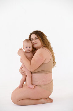 a young plus size mom sitting with her naked child on her knees