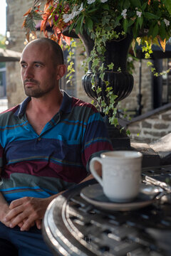 Man Sitting Outside With Coffee in a Sunny Courtyard