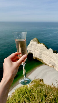 Hand Holding Ros&eacute; Champagne Glass Over White Cliffs and Sea