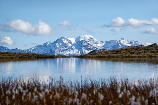 Mountain peaks reflected in alpine tarn with autumn grasses, Valais