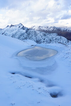 Frozen alpine pond in first winter snow, Swiss Alps