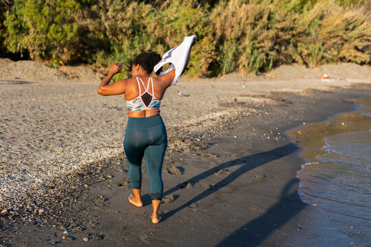 a woman taking off her shirt before going into the water