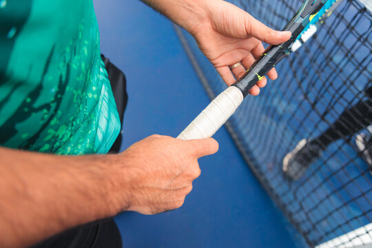 Hands Gripping a Tennis Racket on Court