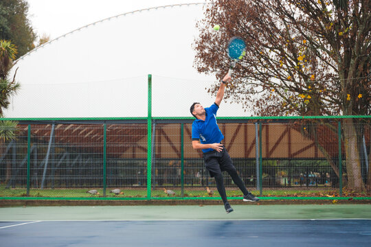 Tennis Player Serving Mid-Air on Outdoor Court