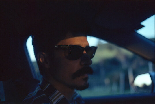 Driver wearing sunglasses at sunset