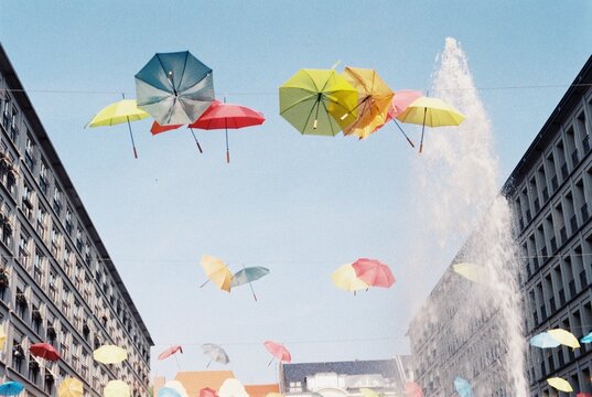 Colorful Umbrellas Floating Above City Street