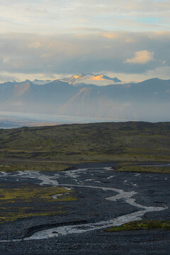 Glacier lit by polar day sun rays and volcanic river 