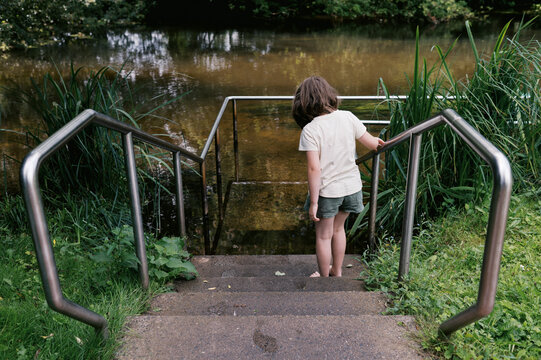 Little girl holding on to rail about to walk into a Kneipp basin