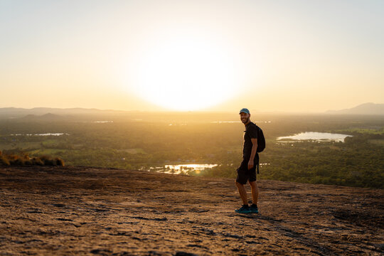 Hiker Enjoys Sunset View From a Rocky Hillside in Nature